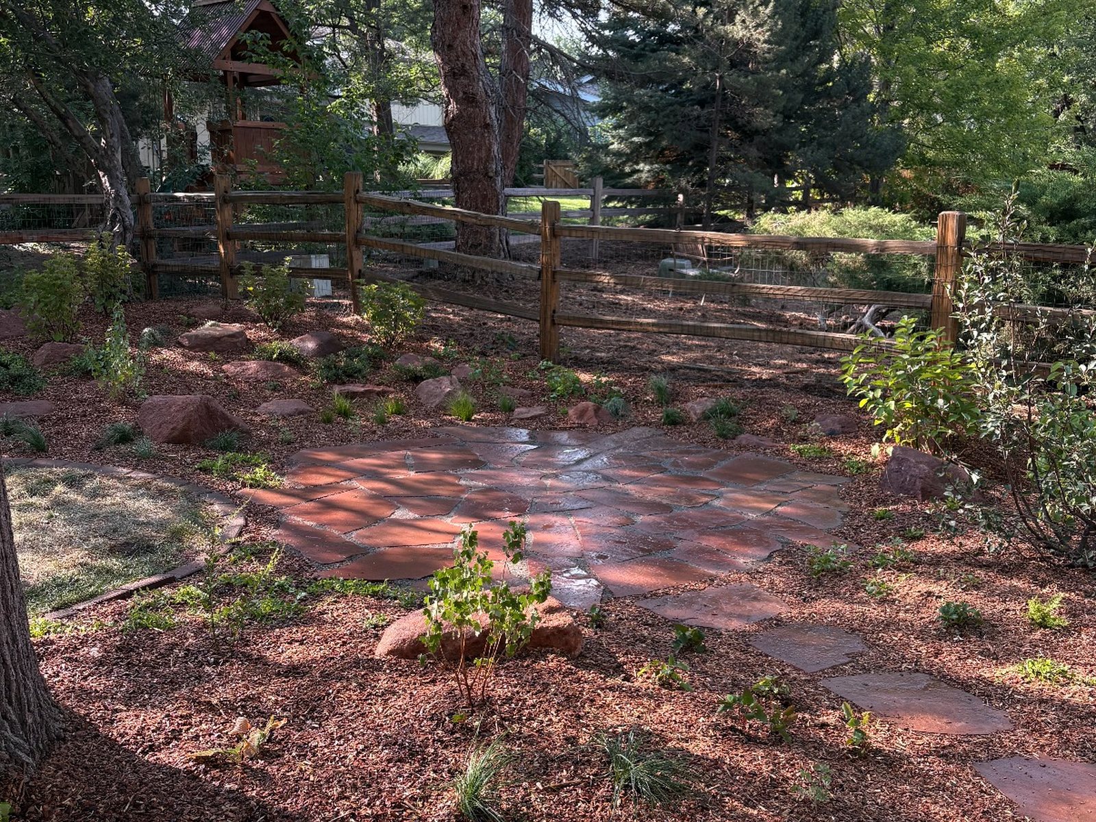Finished backyard: red flagstone patio, mulch beds and new plantings by CJ Landscaping